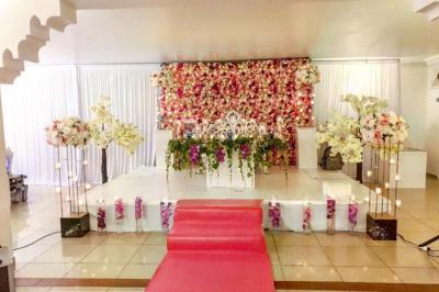 Décor de scène avec colonnes blanches, ornements dorés, rideau rouge et statues sculptées sur les côtés.