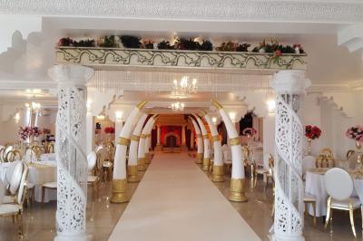 Décor de scène avec colonnes blanches, ornements dorés, rideau rouge et statues sculptées sur les côtés.