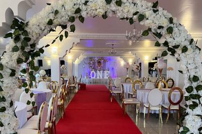 Décor de scène avec colonnes blanches, ornements dorés, rideau rouge et statues sculptées sur les côtés.