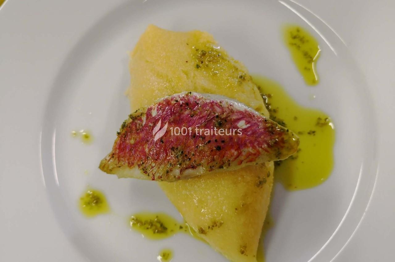 Filet de rouget posé sur une quenelle, nappé d'huile verte et servi dans une assiette blanche.