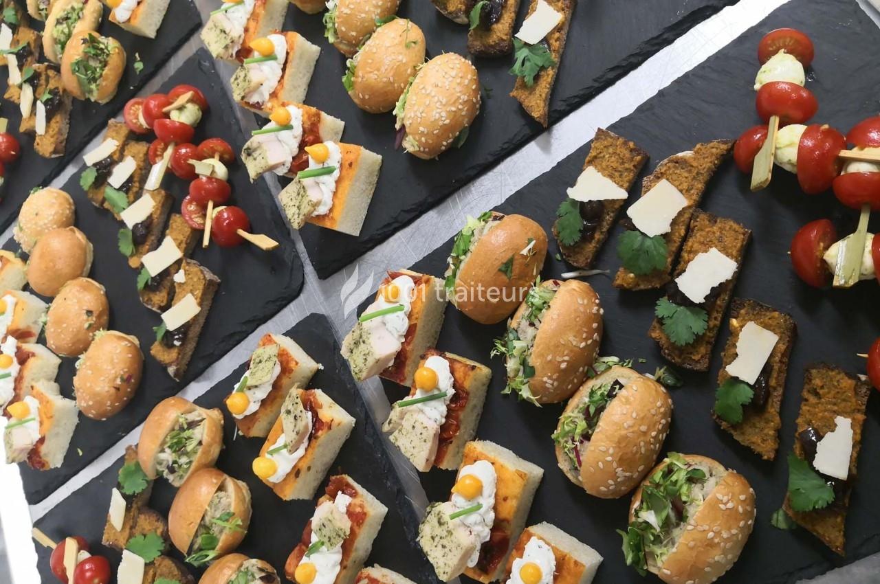 Plateaux de bouchées apéritives variées comprenant mini-burgers, brochettes de légumes et toasts garnis.
