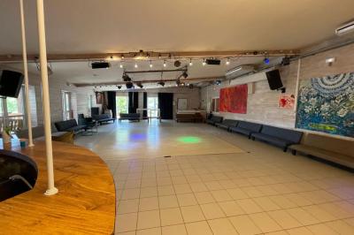 Jardin verdoyant avec des palmiers, des pins et des buissons, baigné de soleil sous un ciel bleu clair.