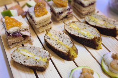 Assiette gastronomique avec un jarret d'agneau, purée de patate douce, gratin et fleurs comestibles, sur une nappe blanche.