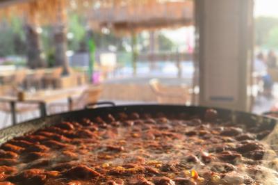 Assiette gastronomique avec un jarret d'agneau, purée de patate douce, gratin et fleurs comestibles, sur une nappe blanche.