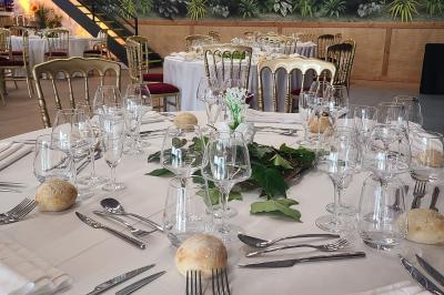 Assiette gastronomique avec un jarret d'agneau, purée de patate douce, gratin et fleurs comestibles, sur une nappe blanche.