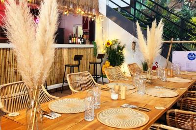 Salle lumineuse avec tables blanches disposées en U, chaises en bois et murs clairs dans un espace modulaire.