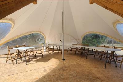 Salle lumineuse avec tables blanches disposées en U, chaises en bois et murs clairs dans un espace modulaire.