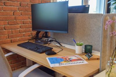 Bureau partagé avec plantes, carte posée sur un support en bois, et personnes travaillant en arrière-plan.