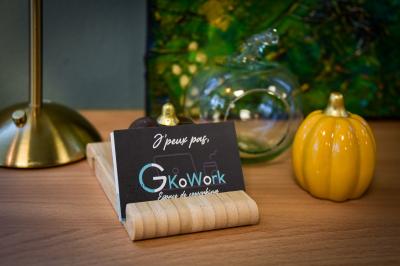 Bureau partagé avec plantes, carte posée sur un support en bois, et personnes travaillant en arrière-plan.