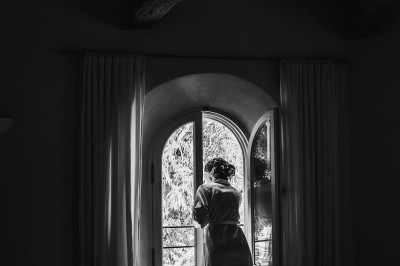 Un couple en tenue de mariage marche main dans la main dans un vignoble, la mariée levant un bouquet.