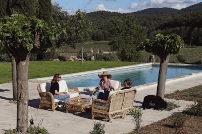Un couple en tenue de mariage marche main dans la main dans un vignoble, la mariée levant un bouquet.