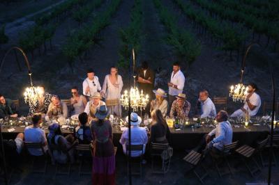 Un couple en tenue de mariage marche main dans la main dans un vignoble, la mariée levant un bouquet.