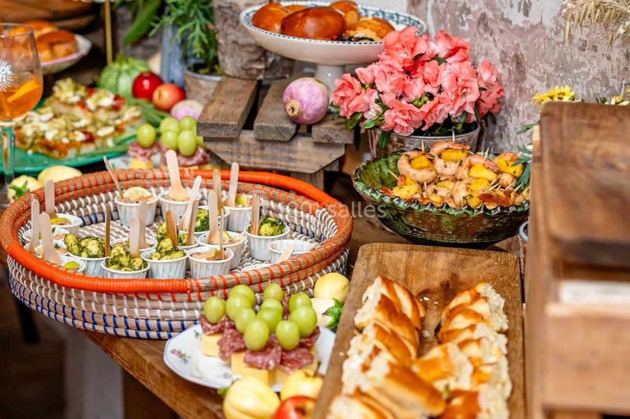 Buffet varié avec fruits, brochettes, viennoiseries et plats salés disposés sur une table en bois.