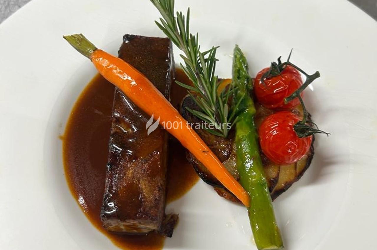 Plat gastronomique composé de viande nappée de sauce, accompagné de carotte, asperge, tomates cerises et pommes de terre.