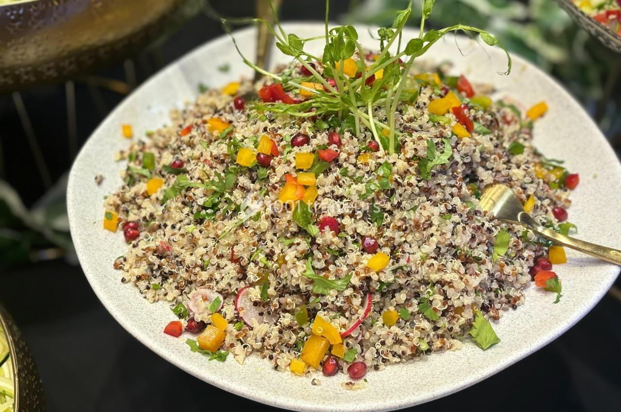 Assiette de salade de quinoa colorée avec légumes variés, herbes fraîches et graines de grenade.