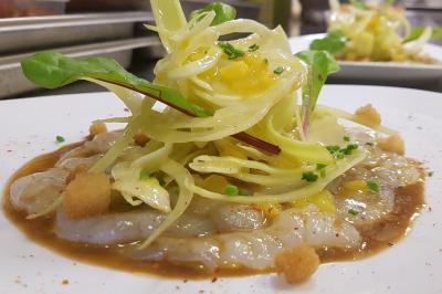 Assiette gastronomique composée de crevettes, légumes, pommes de terre et perles de sauce, présentée avec soin.