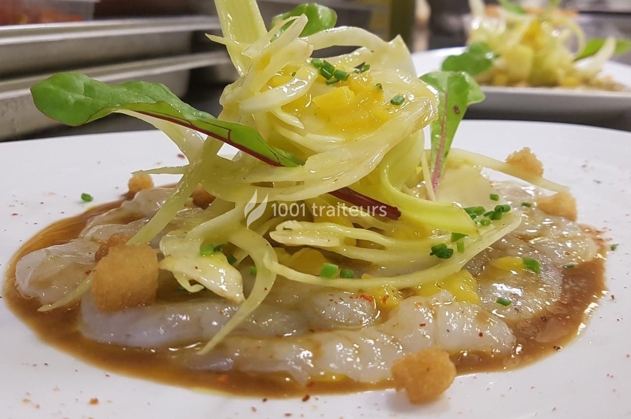 Carpaccio de poisson cru garni de fenouil, croûtons, herbes fraîches et sauce, présenté sur une assiette blanche.