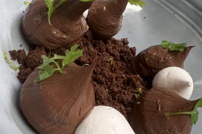 Assiette gastronomique composée de crevettes, légumes, pommes de terre et perles de sauce, présentée avec soin.