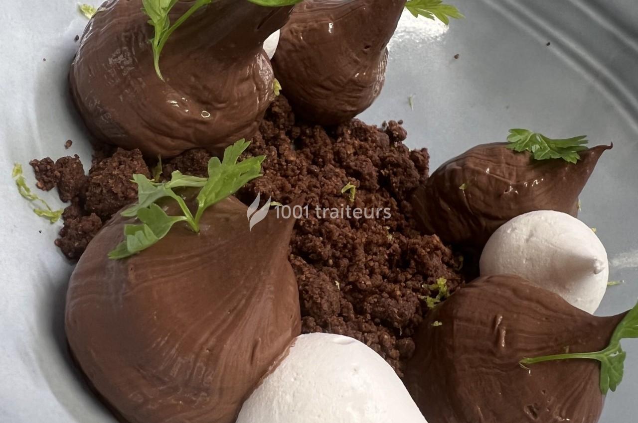 Dessert composé de mousse au chocolat, crumble cacao, meringues blanches et feuilles de persil en décoration.