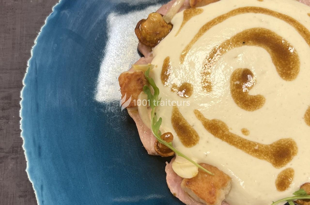 Assiette bleue contenant une préparation crémeuse avec des morceaux de viande, croûtons et garniture verte.