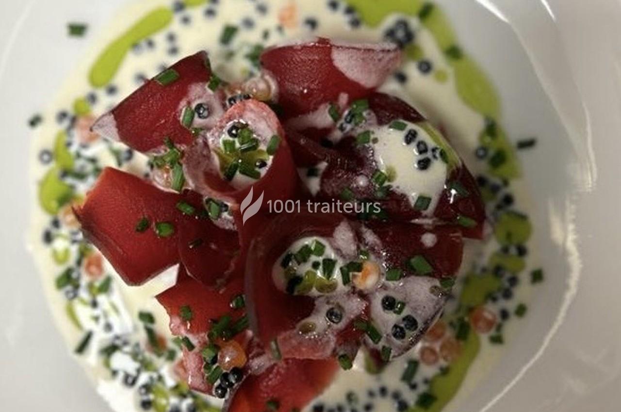 Assiette de ravioles rouges garnies, servies avec une sauce crémeuse, des herbes fraîches et une garniture colorée.