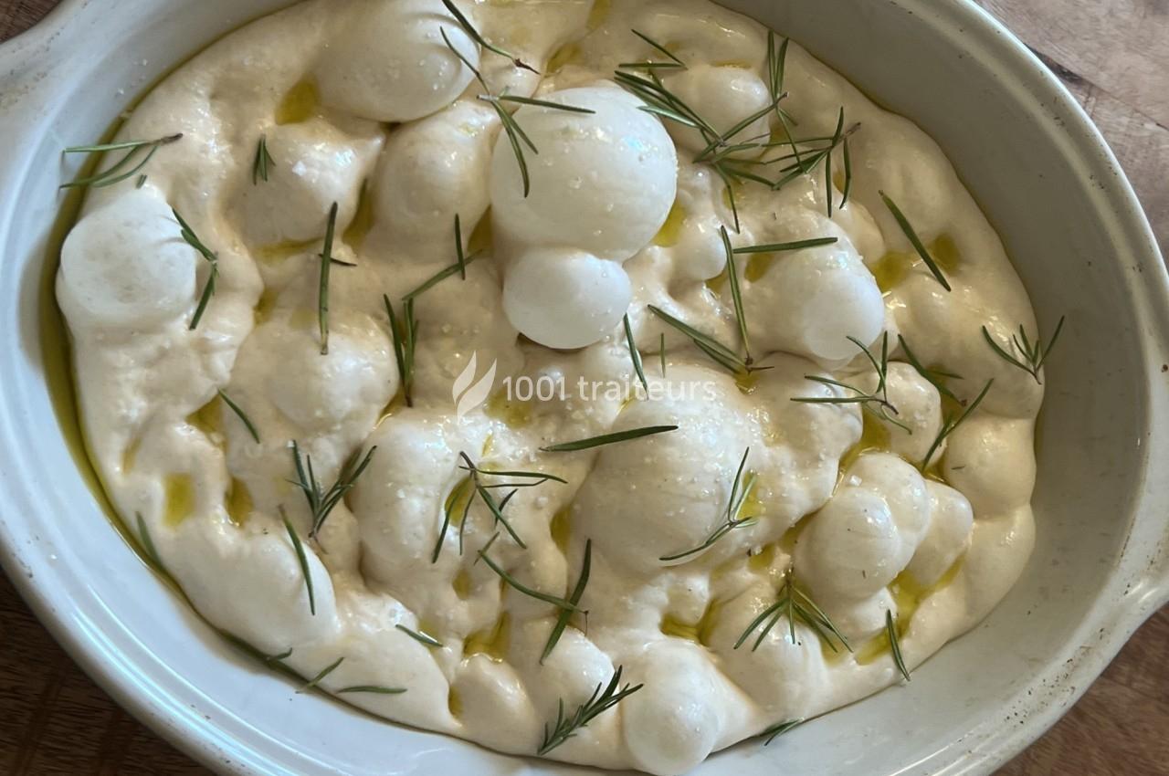 Plat de mousse blanche garnie de brins de romarin frais, présenté dans un bol en céramique blanche.