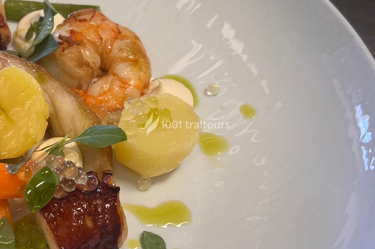 Assiette gastronomique composée de crevettes, légumes, pommes de terre et perles de sauce, présentée avec soin.