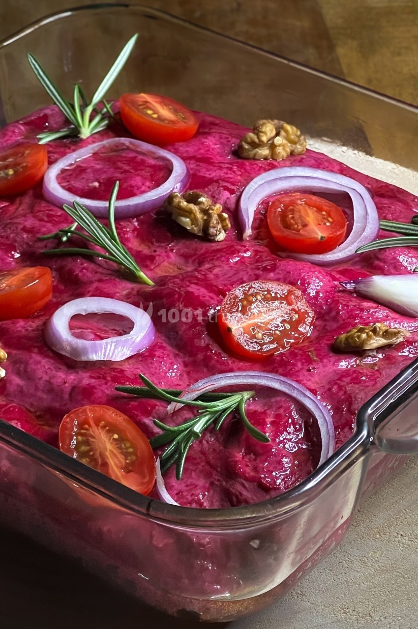 Plat de betterave crémeux garni de rondelles d'oignon rouge, tomates cerises, noix et brins de romarin.