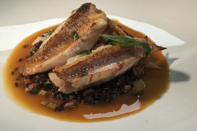 Assiette gastronomique composée de crevettes, légumes, pommes de terre et perles de sauce, présentée avec soin.