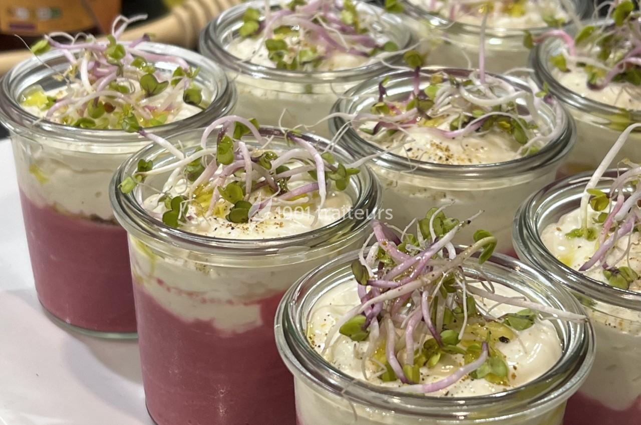 Verrines de mousse rose surmontées de crème blanche, graines germées et éclats de pistaches.