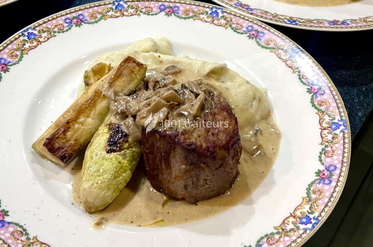 Assiette contenant un filet de viande avec sauce, purée de pommes de terre et légumes grillés, servie sur une vaisselle…