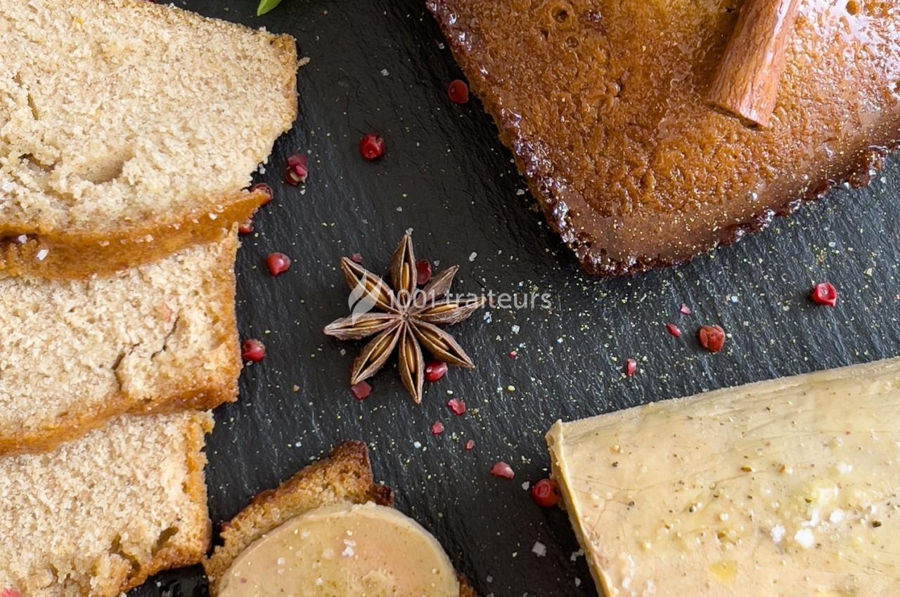 Tranches de pain d'épices, foie gras, étoile de badiane et poivre rose disposés sur une ardoise noire.