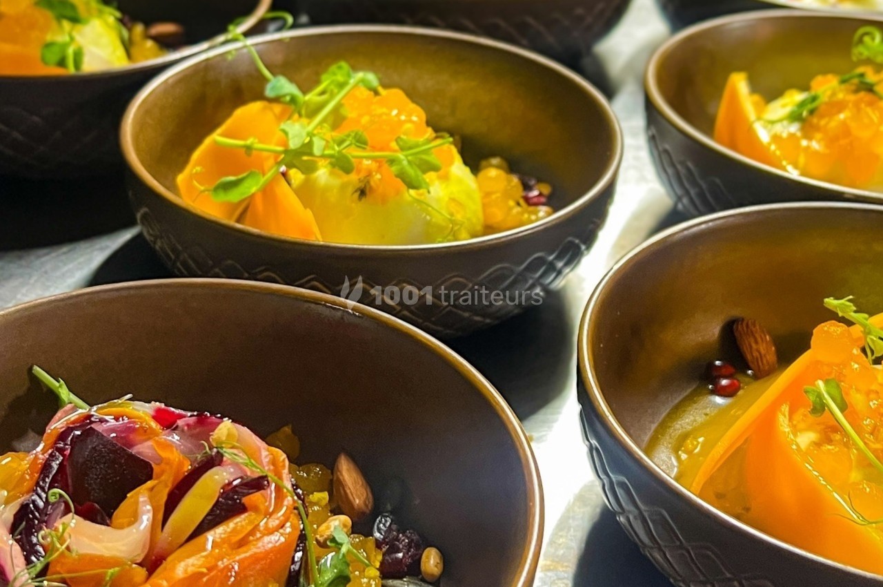 Assiettes individuelles contenant des tranches de légumes colorés, graines, amandes et herbes fraîches.