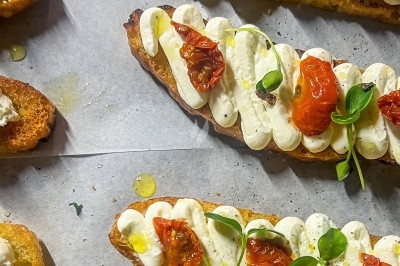 Un chef en tablier marron croise les bras devant un plan de travail dans une cuisine moderne.