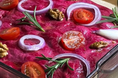 Un chef en tablier marron croise les bras devant un plan de travail dans une cuisine moderne.