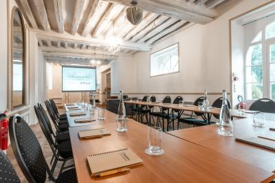 Chambre lumineuse avec lit double, parquet, rideaux orange, lustre et grandes fenêtres donnant sur l'extérieur.