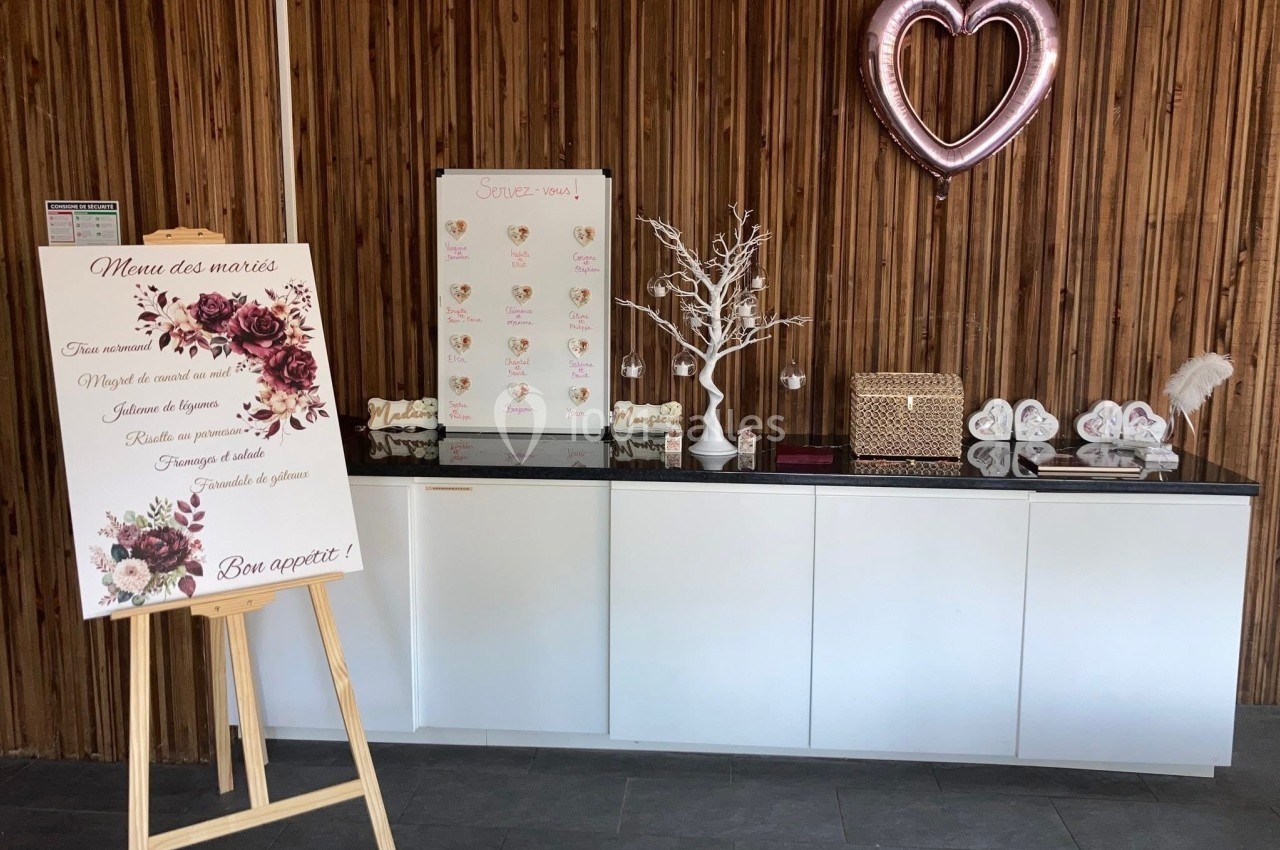 Buffet de mariage avec menu sur chevalet, décorations florales, cœur ballon rose et table ornée d'accessoires.