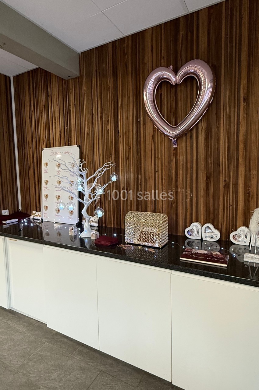 Décoration intérieure avec un comptoir noir, objets décoratifs, ballon en forme de cœur et panneau en bois en arrière-plan.