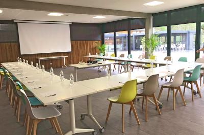 Vue aérienne d'un complexe avec piscines, bâtiments, espaces verts et parkings, entouré de végétation.