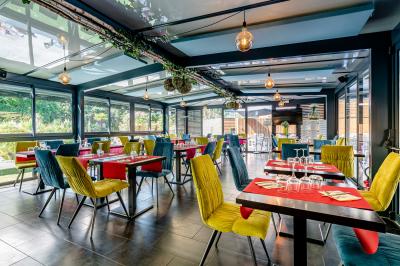 Vue aérienne d'un complexe avec piscines, bâtiments, espaces verts et parkings, entouré de végétation.