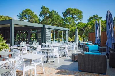 Vue aérienne d'un complexe avec piscines, bâtiments, espaces verts et parkings, entouré de végétation.