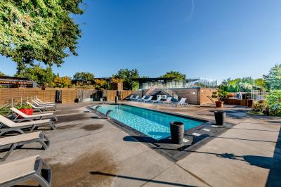 Vue aérienne d'un complexe avec piscines, bâtiments, espaces verts et parkings, entouré de végétation.