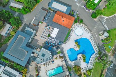 Vue aérienne d'un complexe avec piscines, bâtiments, espaces verts et parkings, entouré de végétation.