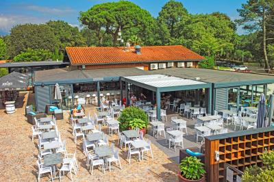 Vue aérienne d'un complexe avec piscines, bâtiments, espaces verts et parkings, entouré de végétation.
