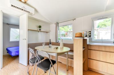 Un enfant avec des brassards orange glisse sur un toboggan rouge dans une piscine extérieure ensoleillée.
