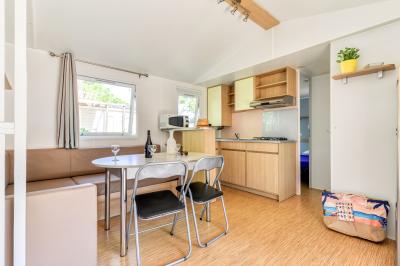Un enfant avec des brassards orange glisse sur un toboggan rouge dans une piscine extérieure ensoleillée.