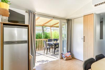 Un enfant avec des brassards orange glisse sur un toboggan rouge dans une piscine extérieure ensoleillée.