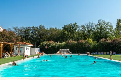 Piscine extérieure avec toboggans, jets d'eau et chaises colorées disposées autour sous un ciel dégagé.