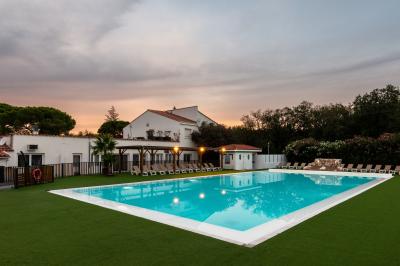 Piscine extérieure avec toboggans, jets d'eau et chaises colorées disposées autour sous un ciel dégagé.