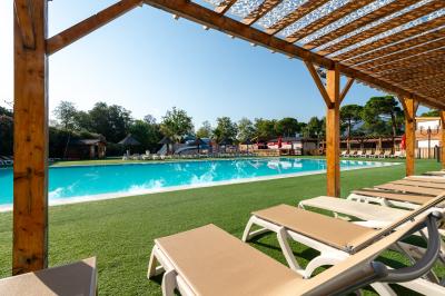 Piscine extérieure avec toboggans, jets d'eau et chaises colorées disposées autour sous un ciel dégagé.